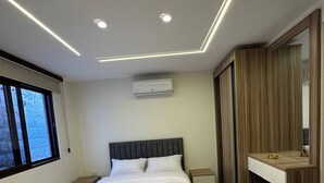 A modern bedroom with a large bed, bedside tables, an air conditioning unit, and a built-in bench. - Xx Antica Jabalal-lwebdeh (Amman)