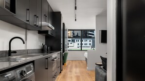 A modern kitchen with a built-in washer and dryer, a large window with a city view, and a minimalist design. - Elegant Tokyo Studio , No Loadshedding (Cape Town)