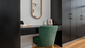 A modern room with a dark wardrobe, a green upholstered chair, a wooden desk, a mirror, and a framed picture. - Elegant Tokyo Studio , No Loadshedding (Cape Town)