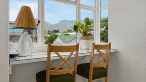 Ein Zimmer mit Blick auf Berge, einer Lampe und zwei Stühlen mit einem Blumentopf an einem Fensterbrett.