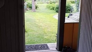Una entrada que da a una terraza de madera con un felpudo y un banco.