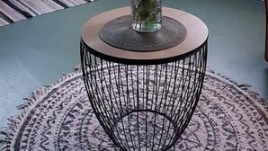 Una habitación con una mesa redonda, un jarrón con flores y vista a espacios verdes.
