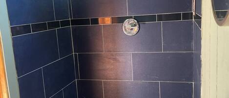 A bathroom with dark blue tiles, a shower, and a sink with a chrome faucet.