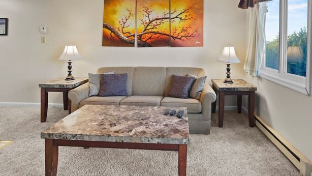 A living room with a sofa, coffee table, and two side tables with lamps. A large painting is on the wall above the sofa. - ML365 Slope Side Getaway in Snowshoe Sleeps 6 WiFi (Snowshoe)