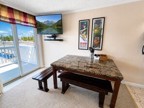 A room with a television, a table with a granite top, a bench, and a view of a mountain through a window. - ML365 Slope Side Getaway in Snowshoe Sleeps 6 WiFi (Snowshoe)
