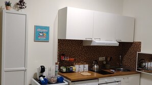 A compact kitchen with a washing machine, a small refrigerator, and a microwave.