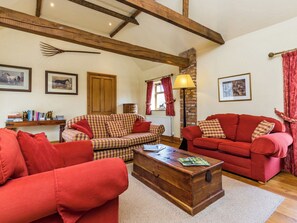 A cozy living room with a wooden coffee table, two red sofas, a checkered sofa, and a fireplace.