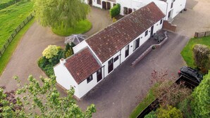 A large white building with a red-tiled roof, surrounded by green fields and a tree. - 2 bedroom accommodation in Louth (Louth)