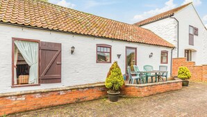 A white building with a tiled roof, a brick lower level, and a paved courtyard. - 2 bedroom accommodation in Louth (Louth)