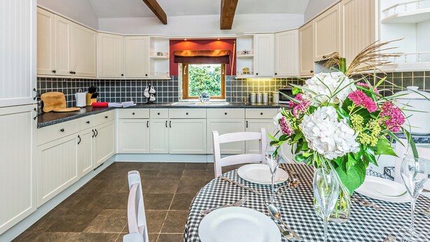 A modern kitchen with white cabinets, a checkered tablecloth, and a vase of flowers. - 2 bedroom accommodation in Louth (Louth)