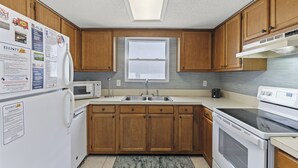 A kitchen with wooden cabinets, a microwave, a sink, and a stove.