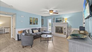 A living room with a gray sofa, a round coffee table, and a fireplace.