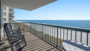 A balcony with a view of the beach and ocean.