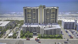 A high-rise hotel with multiple floors, a parking garage, and a view of the beach.