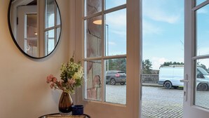 A room with a large window, a mirror, and a table with a vase of flowers. - The Police Station - UK45642 (Silloth)