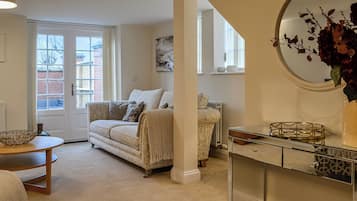 A living room with a beige sofa, a glass coffee table, and a decorative mirror.