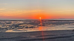 A sunset over a coastal landscape with a visible city skyline in the distance. - The Police Station - UK45642 (Silloth)