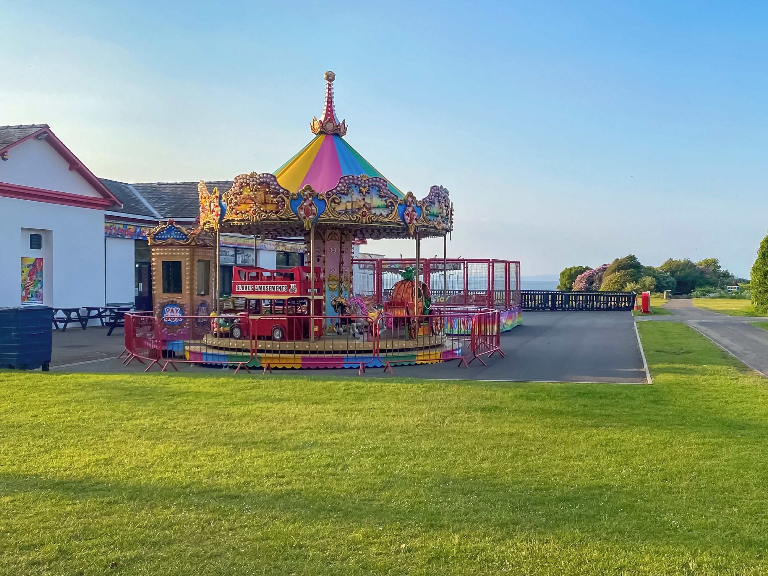 A carousel with a colorful, ornate top and a red car in the center.