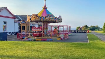 A carousel with a colorful, ornate top and a red car in the center.