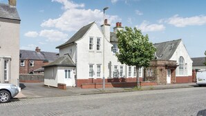 A traditional two-story house with a brick facade and white trim, a cobblestone driveway, and a tree in front. - The Police Station - UK45642 (Silloth)
