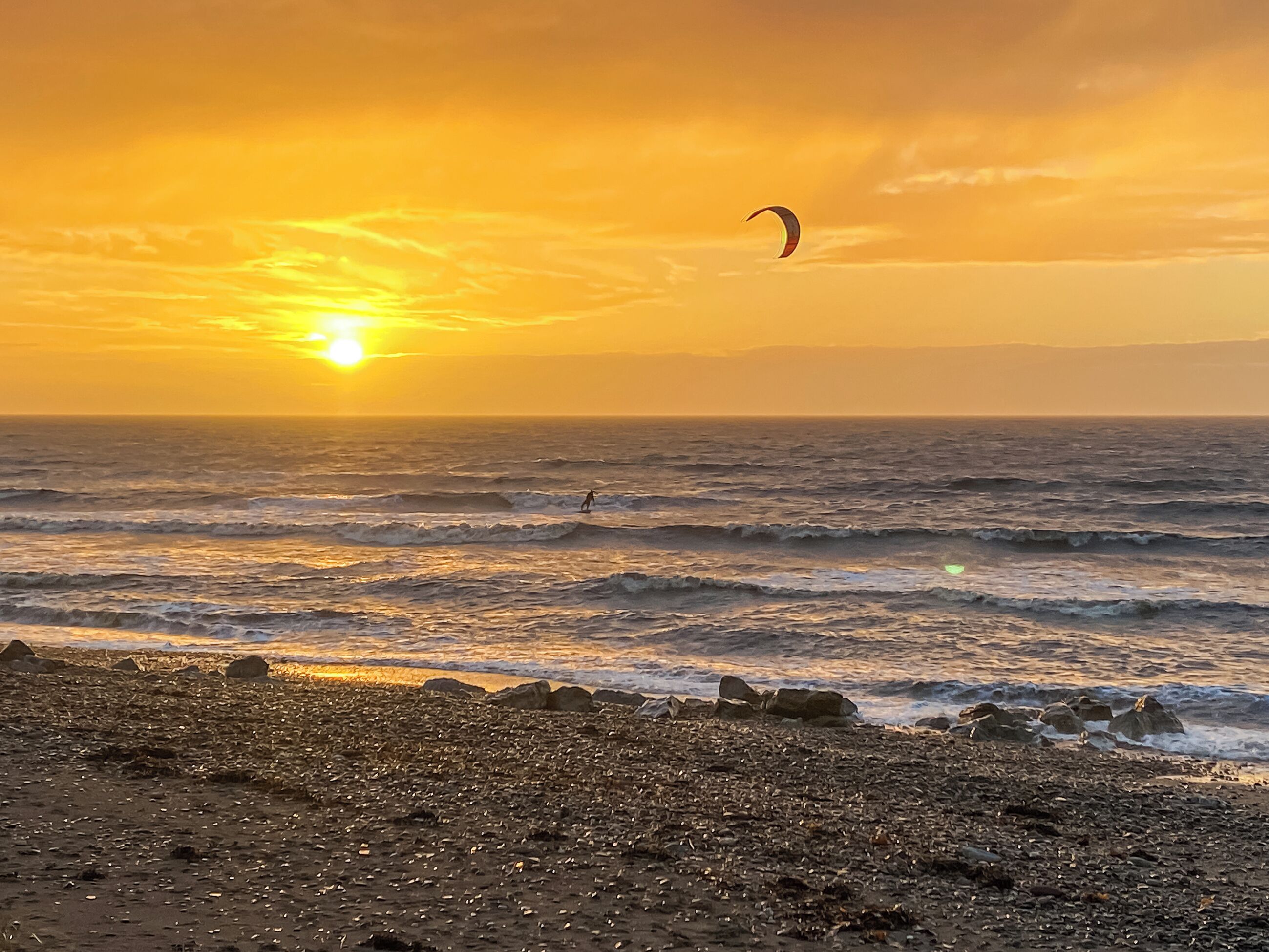 Uma praia com ondas e um pôr do sol.