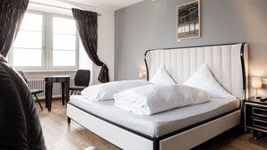A modern bedroom with a large bed, a desk, and a chair. - Eventlocation & Hotel Schloss Neuburg (Obrigheim)