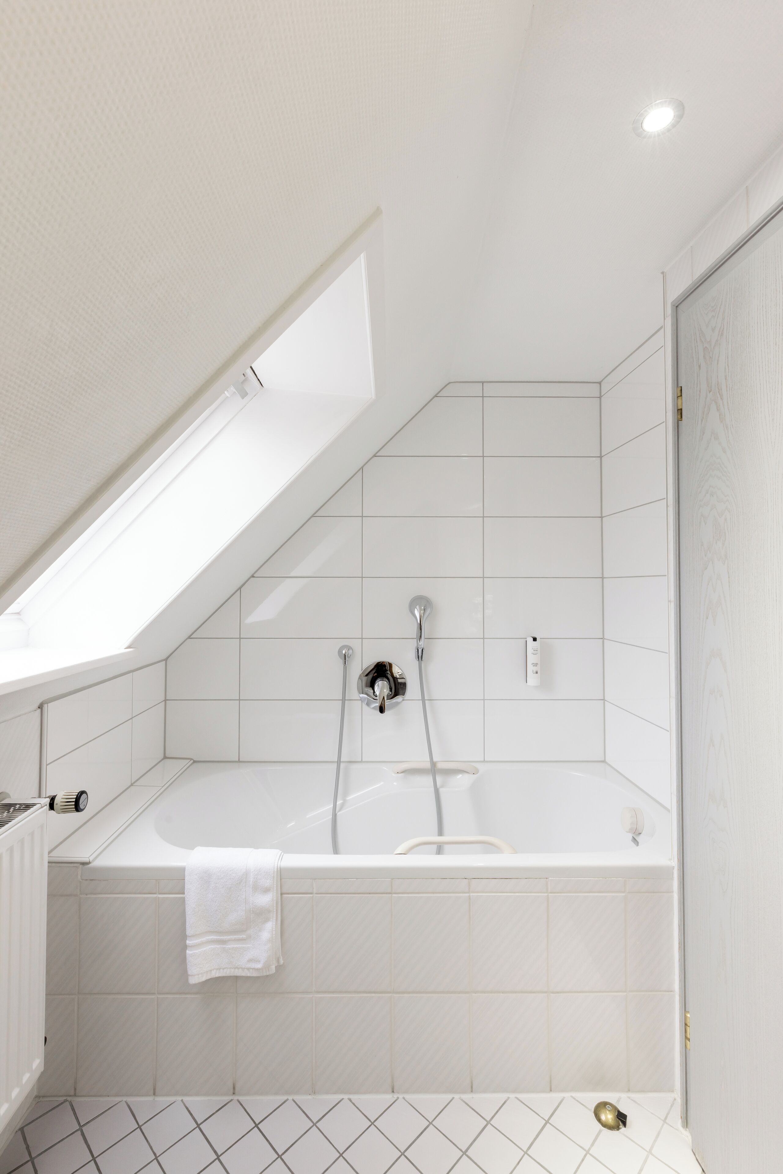 A modern bathroom with a skylight, a bathtub, and a shower.