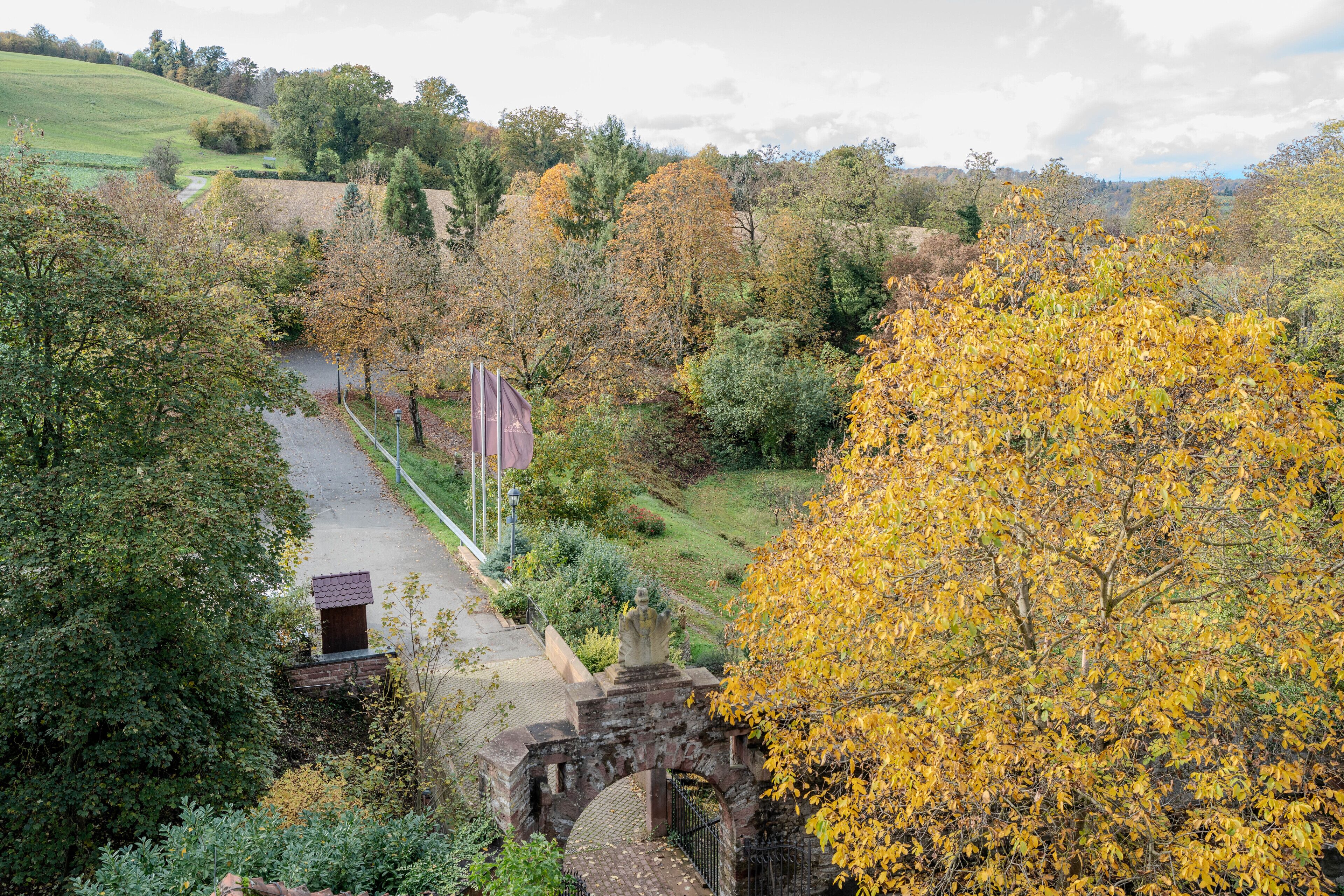Ein Park mit einer Steinbrücke, einer Statue und einem Weg.