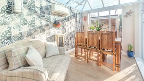 A conservatory with a glass ceiling, a wooden dining table, and a sofa with plaid cushions. - A fabulous seaside retreat, ideal for couples, friends, or small families. (Hayling Island)
