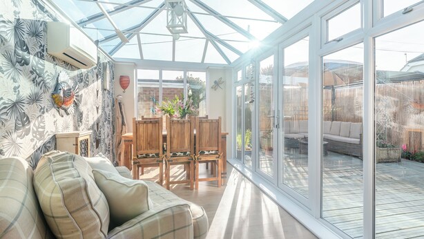 A conservatory with a glass ceiling, a dining area with wooden furniture, and a view of the backyard. - A fabulous seaside retreat, ideal for couples, friends, or small families. (Hayling Island)