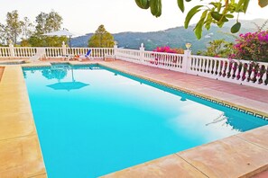 Une piscine rectangulaire, dotée d’une balustrade blanche et entourée d’une terrasse carrelée.