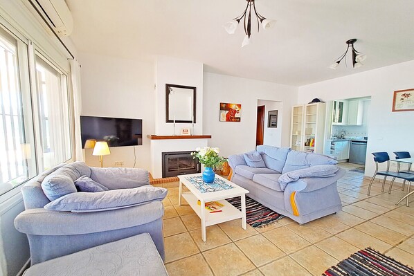 A living room with a fireplace, a television, and a dining area with chairs and a table.