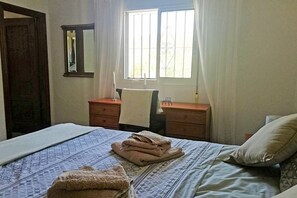 A bedroom with a bed, a nightstand, a dresser, a window with curtains, and a mirror on the wall. - Villa Sinsonte (Torrox)