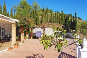 A patio area with a pergola, potted plants, and a stone wall.