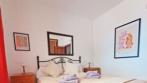Une chambre à coucher avec un lit, une table de chevet, un miroir et des œuvres d’art accrochées aux murs.
