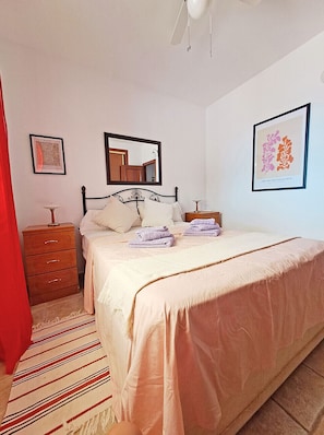 Une chambre à coucher avec un lit, une table de chevet, un miroir et des œuvres d’art accrochées aux murs.
