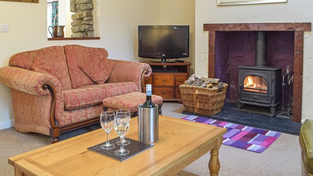 A living room with a sofa, a television, a fireplace, and a table with glasses. - Picked for its character and only a 5 minute drive to the beach. (Keeston)