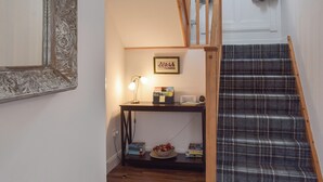 A staircase with a plaid carpet, a wooden handrail, and a small table with a lamp and books. - 3 bedroom accommodation in Dunoon (Dunoon)