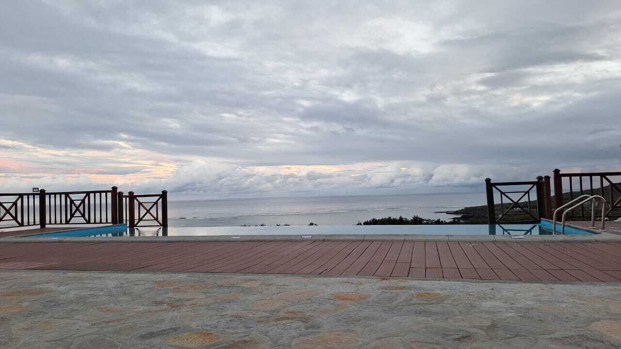 A wooden deck with a pool and a view of the sea.