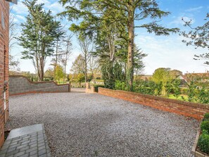 A gravel patio with brick walls and a brick pathway leading to a gate.