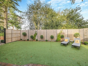 A backyard with artificial grass, a wooden fence, and three lounge chairs with cushions. - 3 bedroom accommodation in Beverley (Beverley)