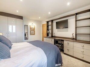 Un dormitorio con cama, escritorio, armario y televisor.