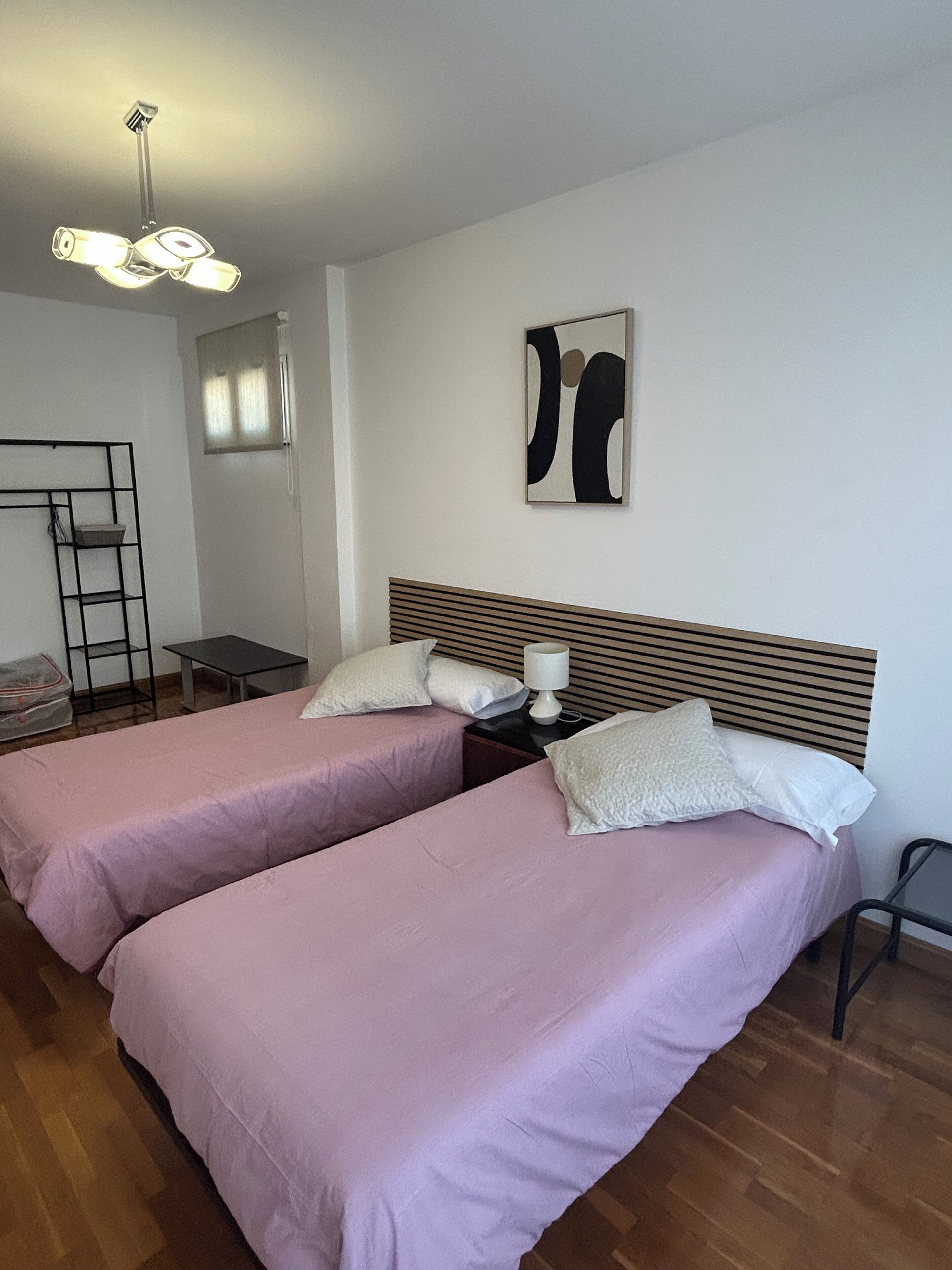 Une pièce avec deux lits, un bureau, une chaise, une échelle et un luminaire fixé au plafond.