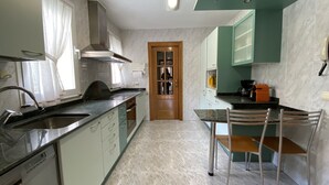A modern kitchen with a central island, stainless steel appliances, and a dining area with a table and chairs.