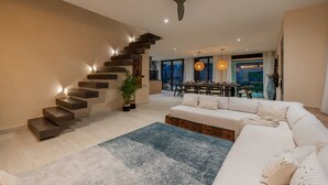 A modern living room with a staircase, a dining area, and a large window. - Villa Tovar Tulum / Private Pool/ Starlink Wi-Fi / Mayan Jungle.  (Tulum)