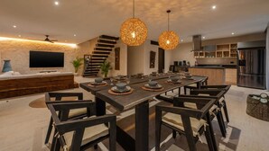 A modern dining area with a long table, dark chairs, and hanging pendant lights. - Villa Tovar Tulum / Private Pool/ Starlink Wi-Fi / Mayan Jungle.  (Tulum)