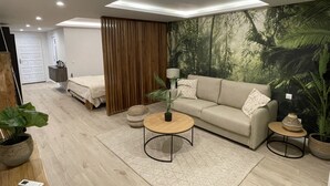 Una sala de estar moderna con un sofá, una mesa de centro y un mural de un bosque.