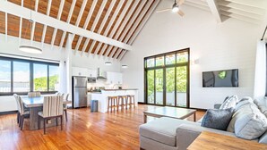 Amplia sala de estar con suelo de madera, una mesa de comedor, un sofá y una cocina al fondo.
