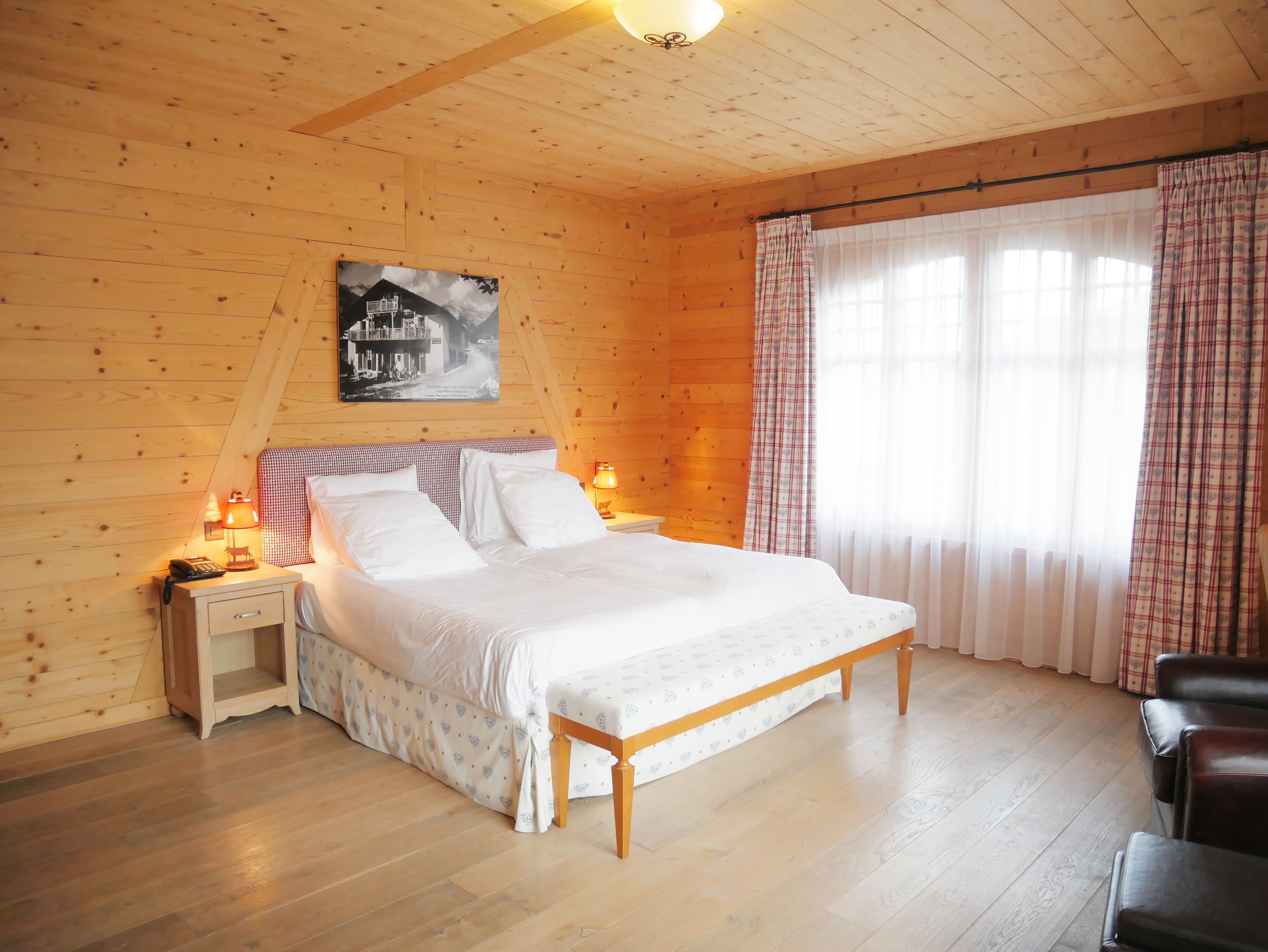 A wooden-paneled bedroom with a bed, nightstands, and a lamp.