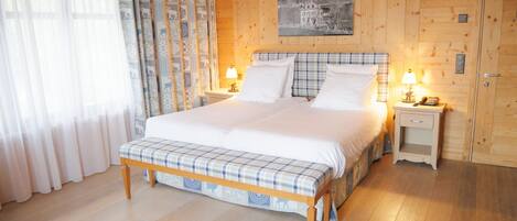 A wooden-paneled bedroom with a bed, two bedside tables with lamps, and a painting on the wall.